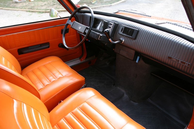 Intérieur Renault 5 d'origine avec levier de vitesse sur planche de bord et intérieur orange couleur carrosserie.